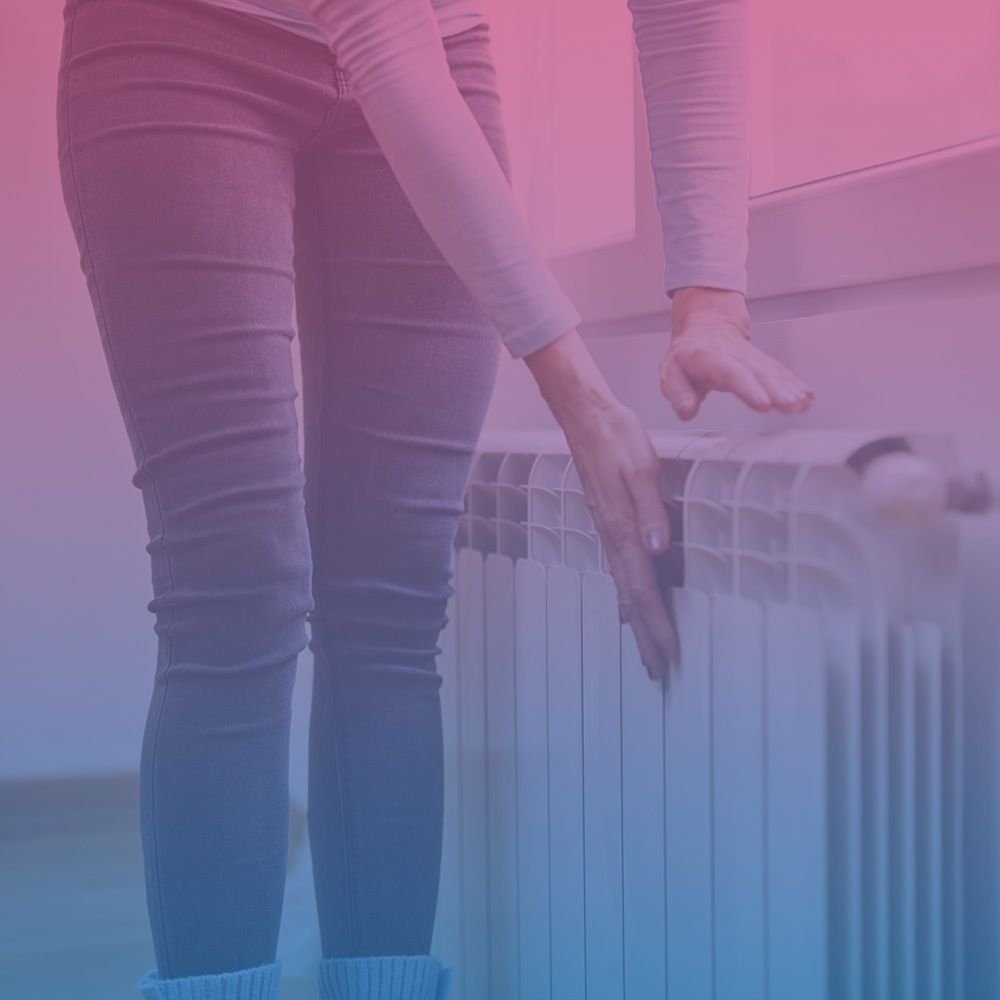 Frau überprüft mit den Händen, ob die Heizung warm ist